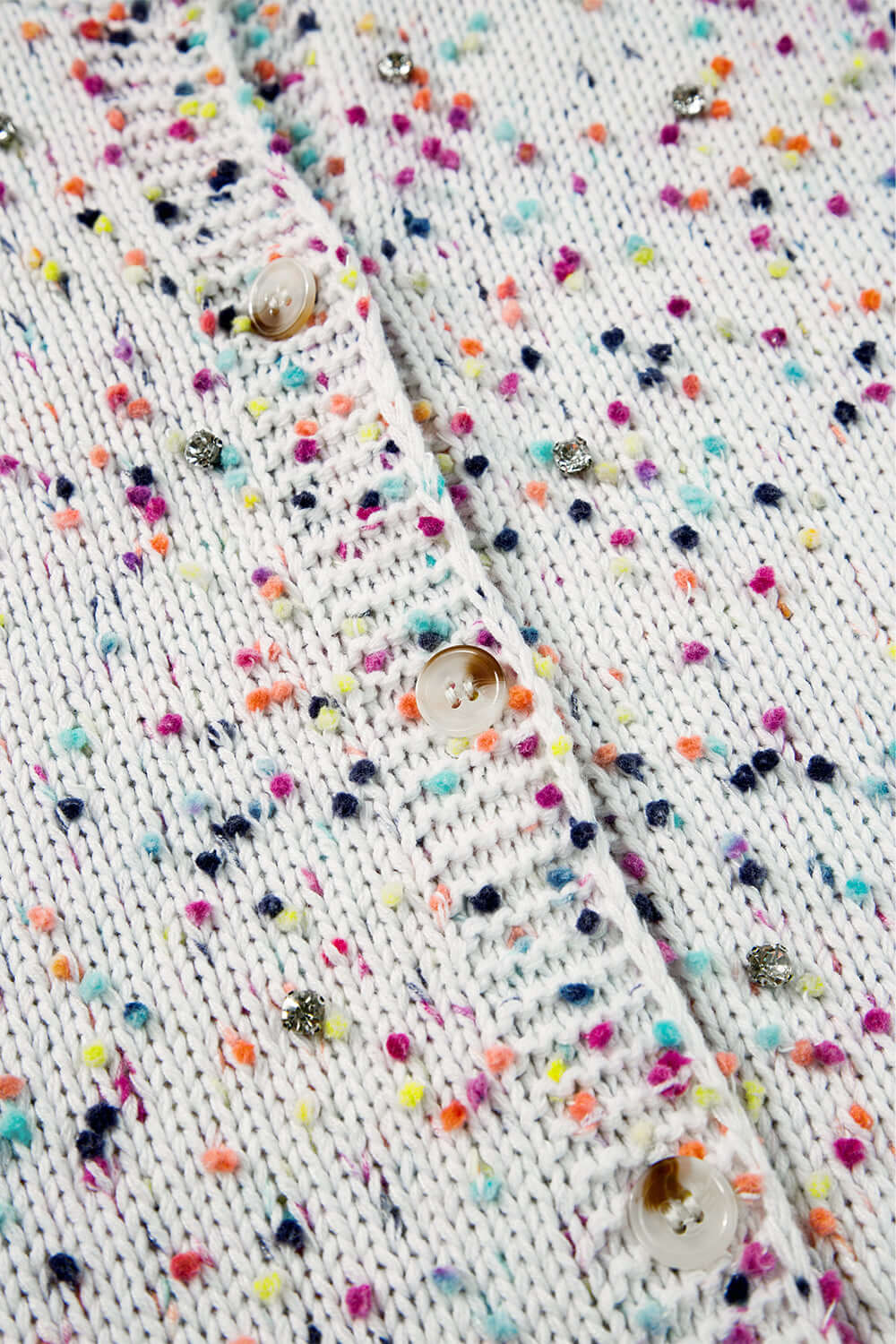 Close-up of a soft white knit cardigan with subtle shimmer details.