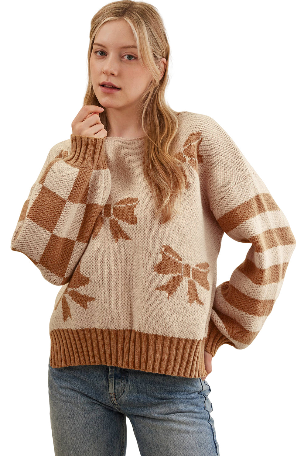 Woman wearing a beige sweater with brown bow patterns and blue jeans on a white background