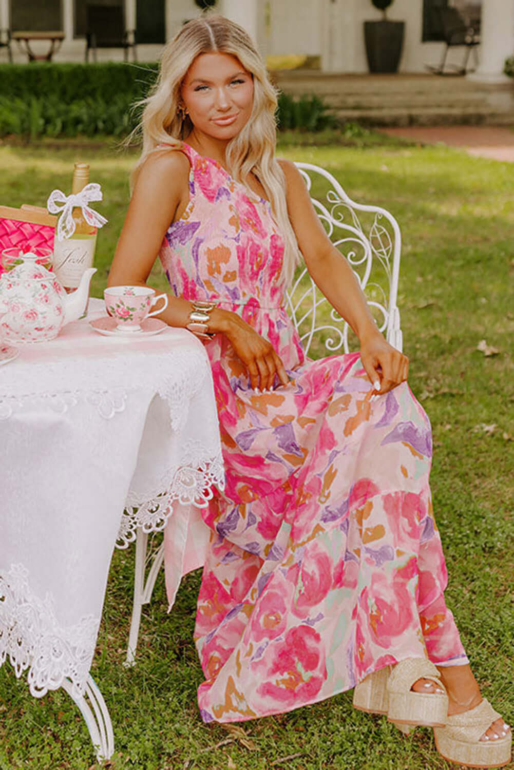 Rosy Sunset One-Shoulder Dress. Sitting model. Outdoor setting.
