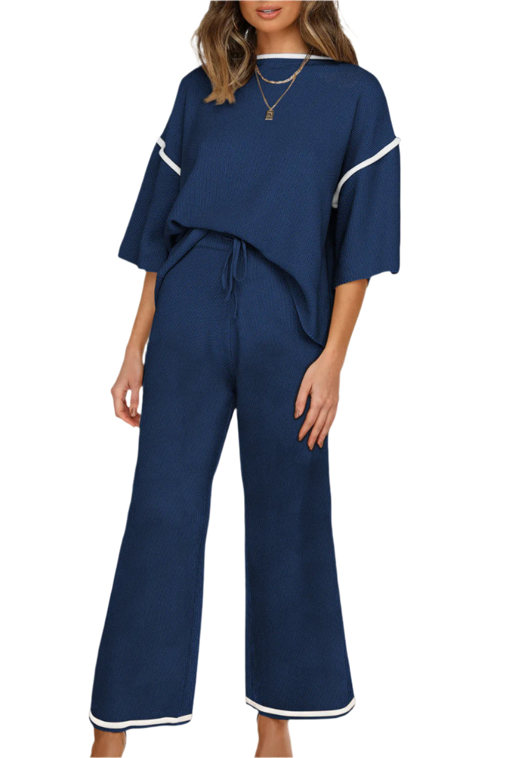 Woman wearing a navy blue outfit with white trim on a plain background