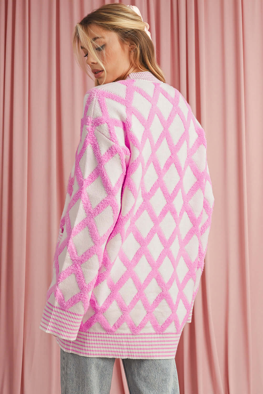Back view of a women's oversized knit cardigan in a pink check print.