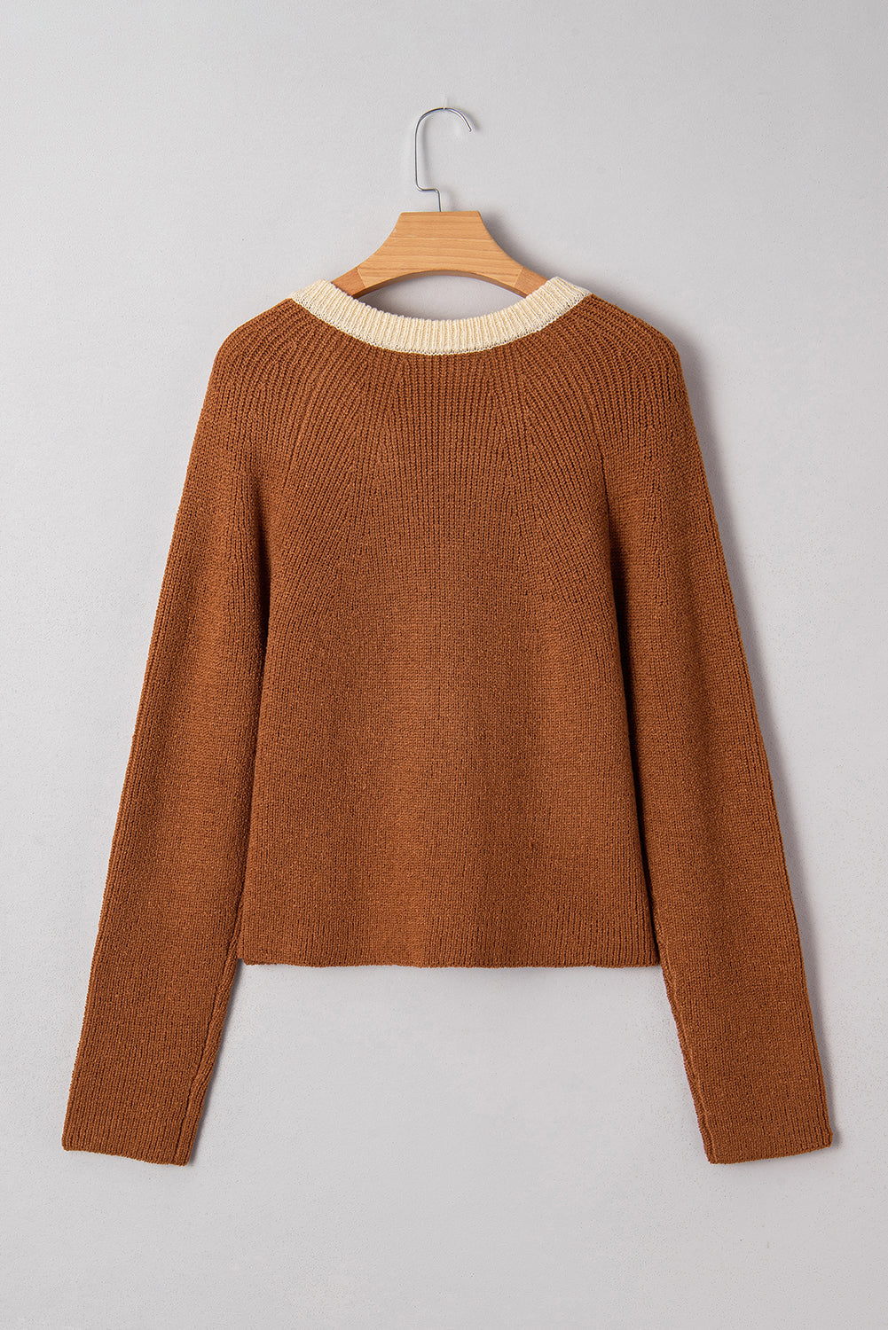 Brown sweater on a wooden hanger against a gray background