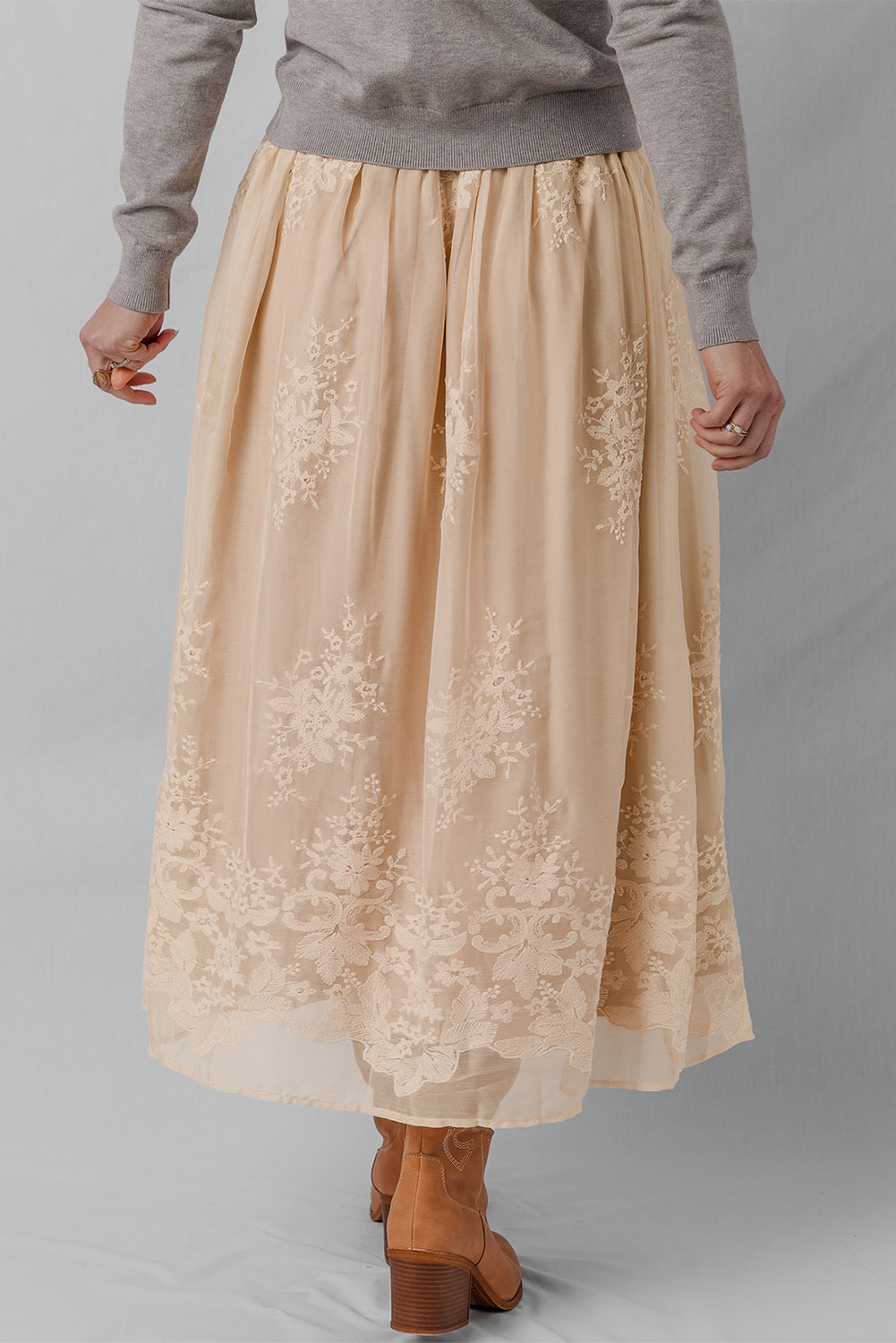 Beige lace skirt worn by a person on a gray background