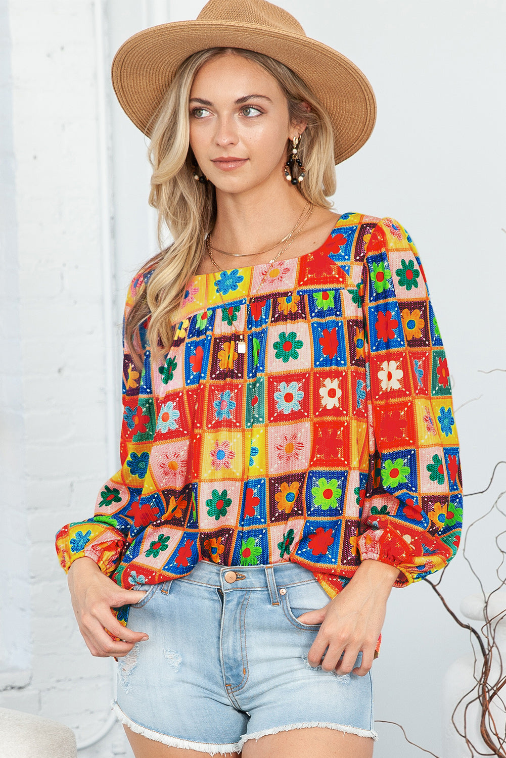 Woman wearing a colorful patterned blouse and denim shorts against a white background