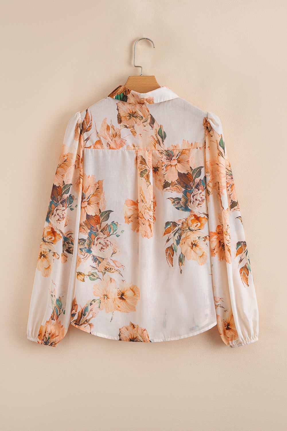 Floral blouse on a hanger against a beige background