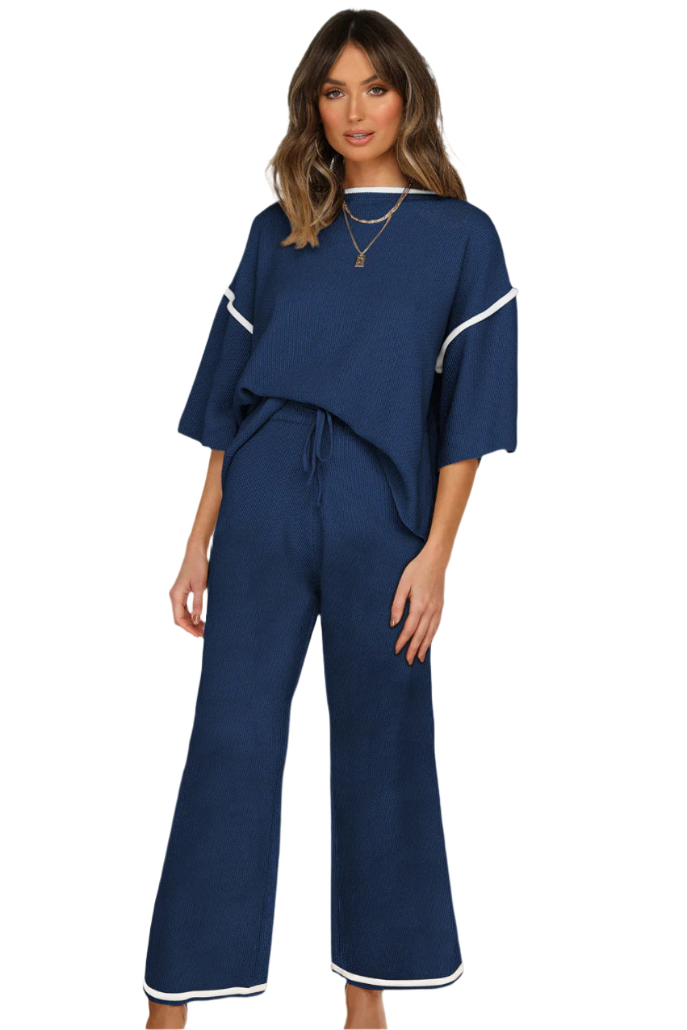 Woman wearing a navy blue outfit with white trim on a white background