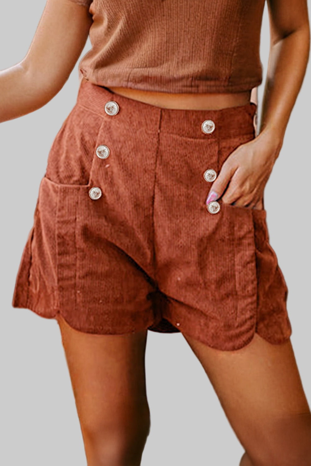 Person wearing brown shorts with button details in an indoor setting