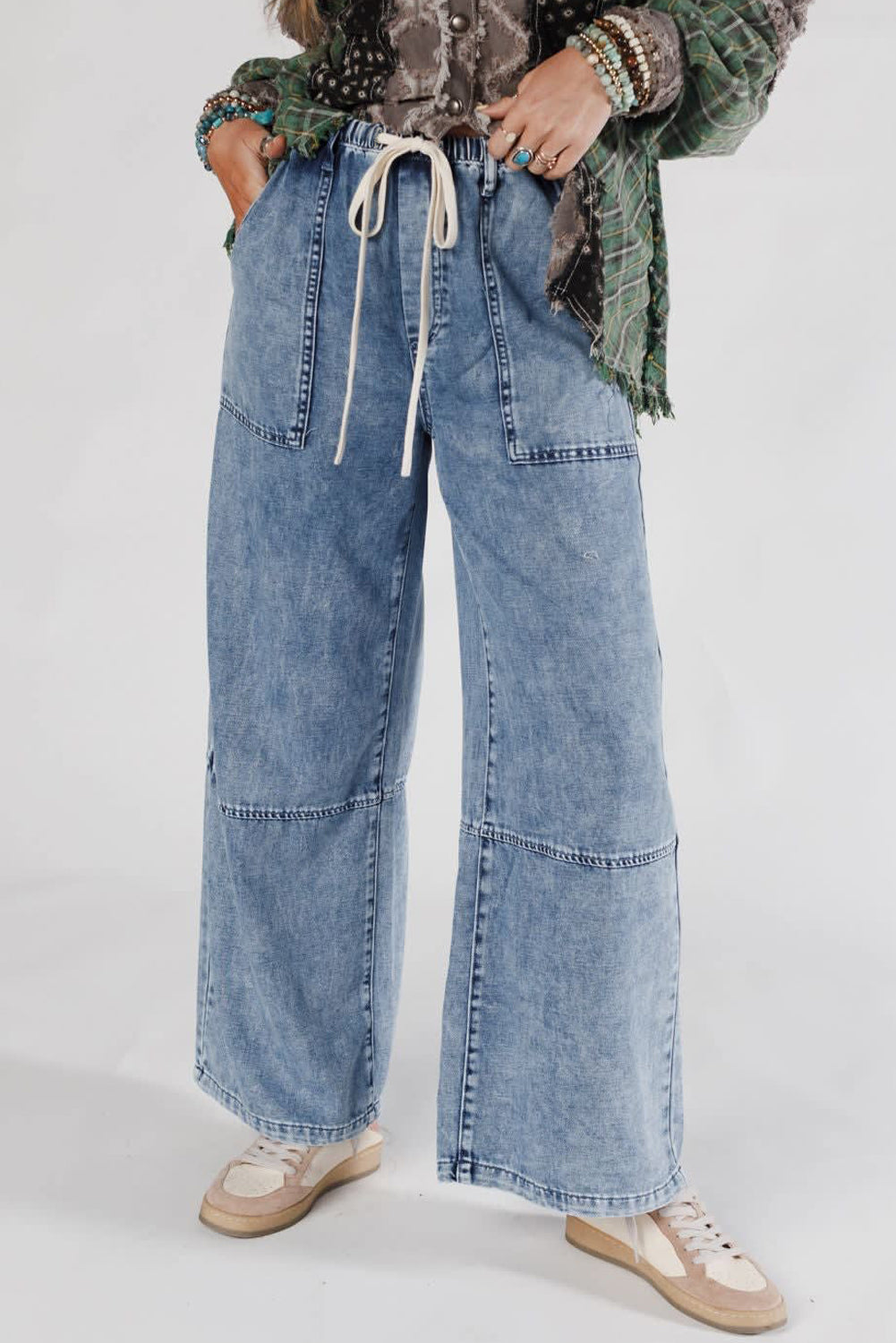 Person wearing wide-leg blue jeans with a plain background