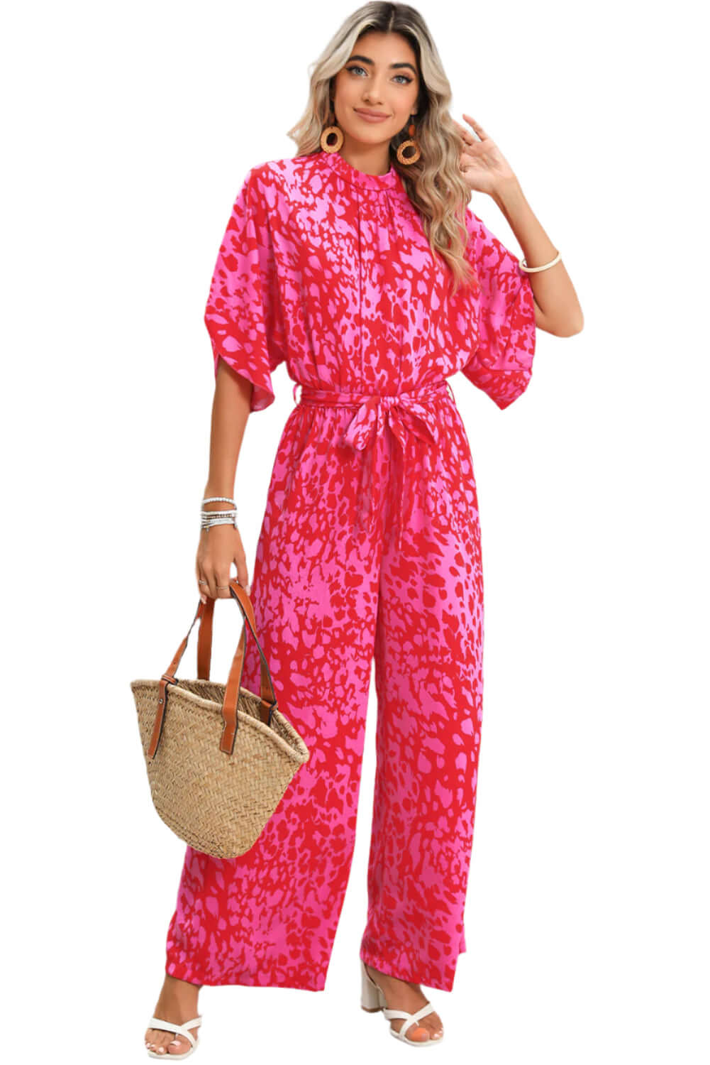 Woman wearing a hot pink wide-leg jumpsuit with a bold print and tie waist.
