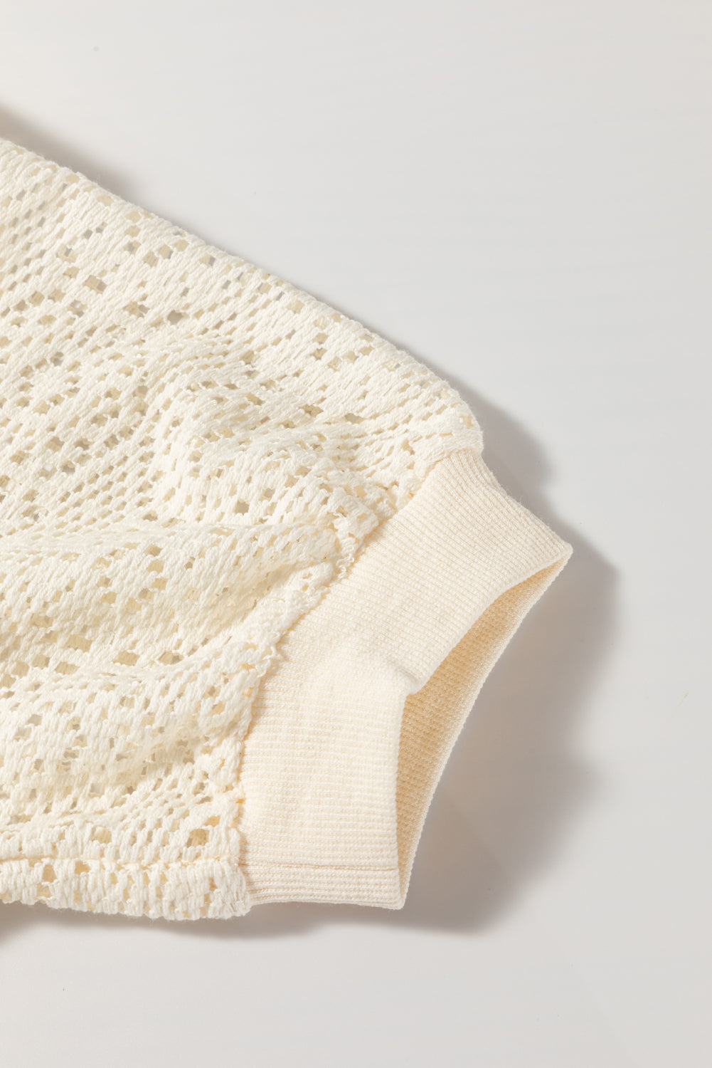 Close-up of a textured cream-colored fabric on a light gray background