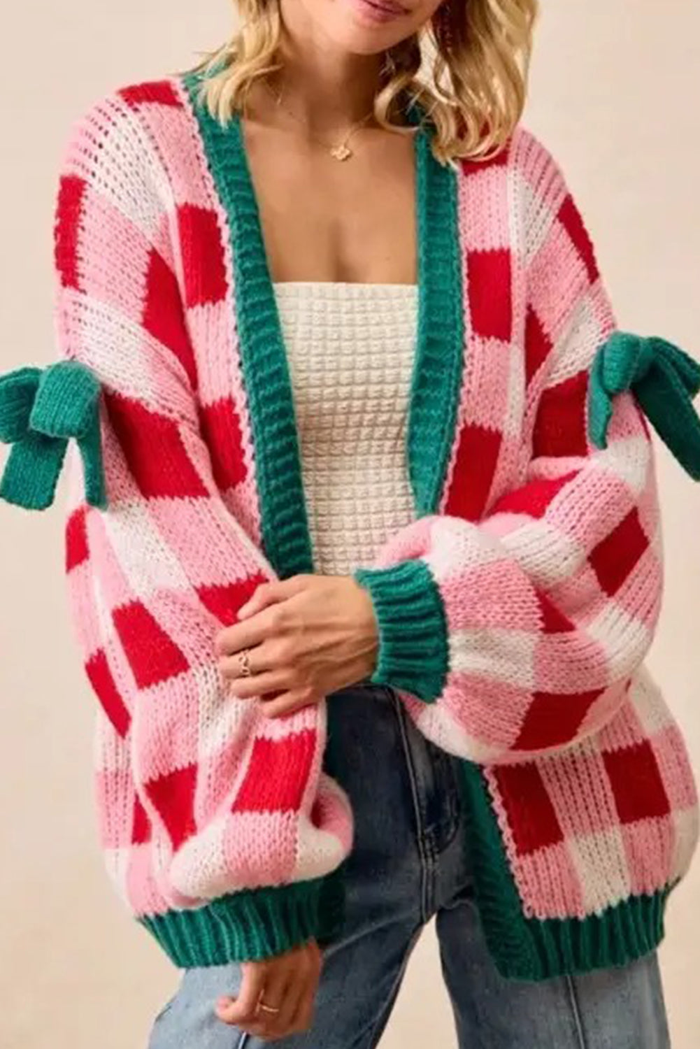 Person wearing a red and pink plaid cardigan with green trim on a beige background