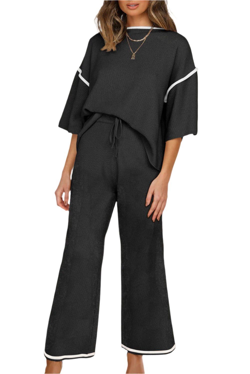 Black outfit with white trim worn by a model on a white background