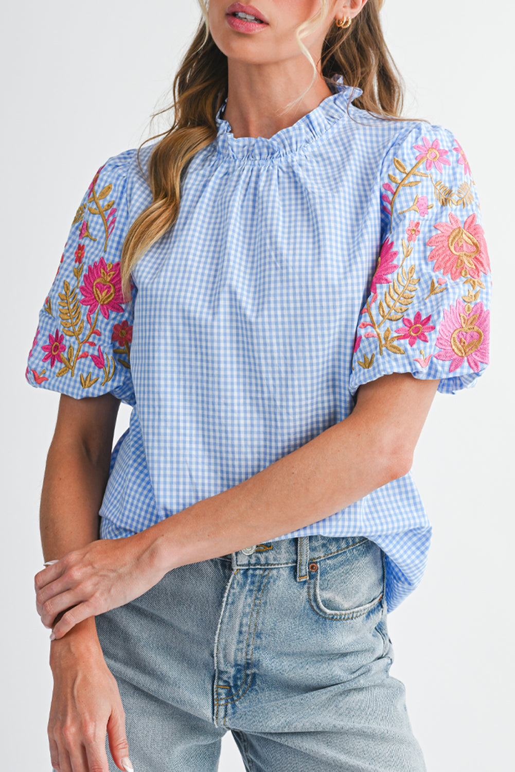 Woman wearing a blue checkered top with floral sleeves on a white background