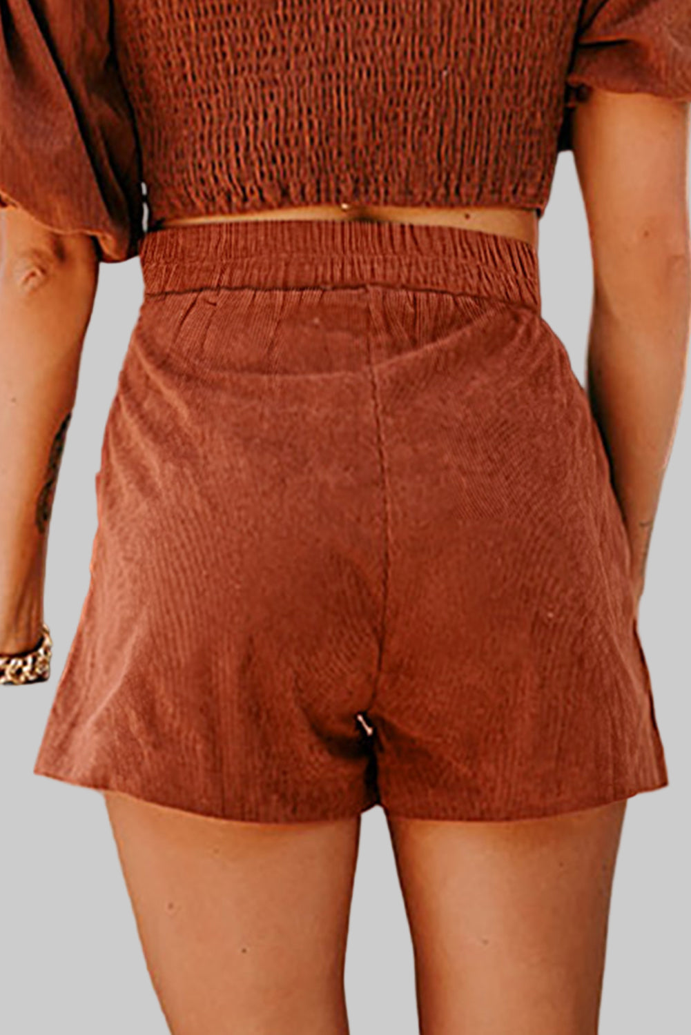 Person wearing brown shorts and top against a neutral background