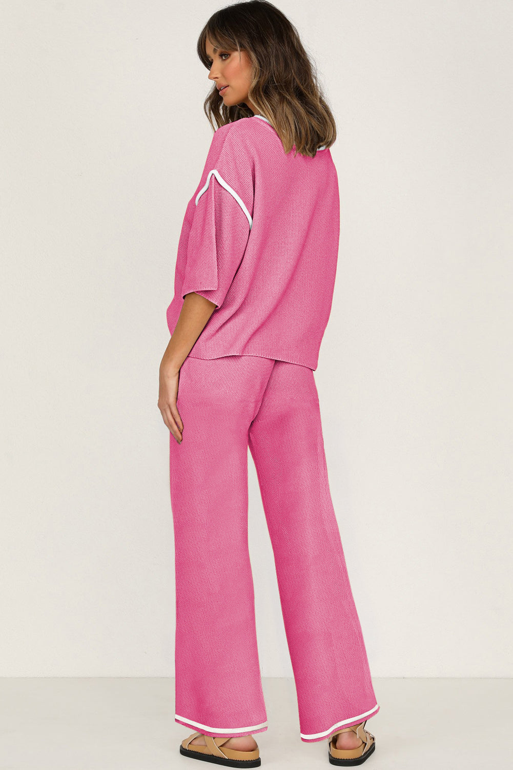 Woman wearing a pink outfit with a white logo on a plain background