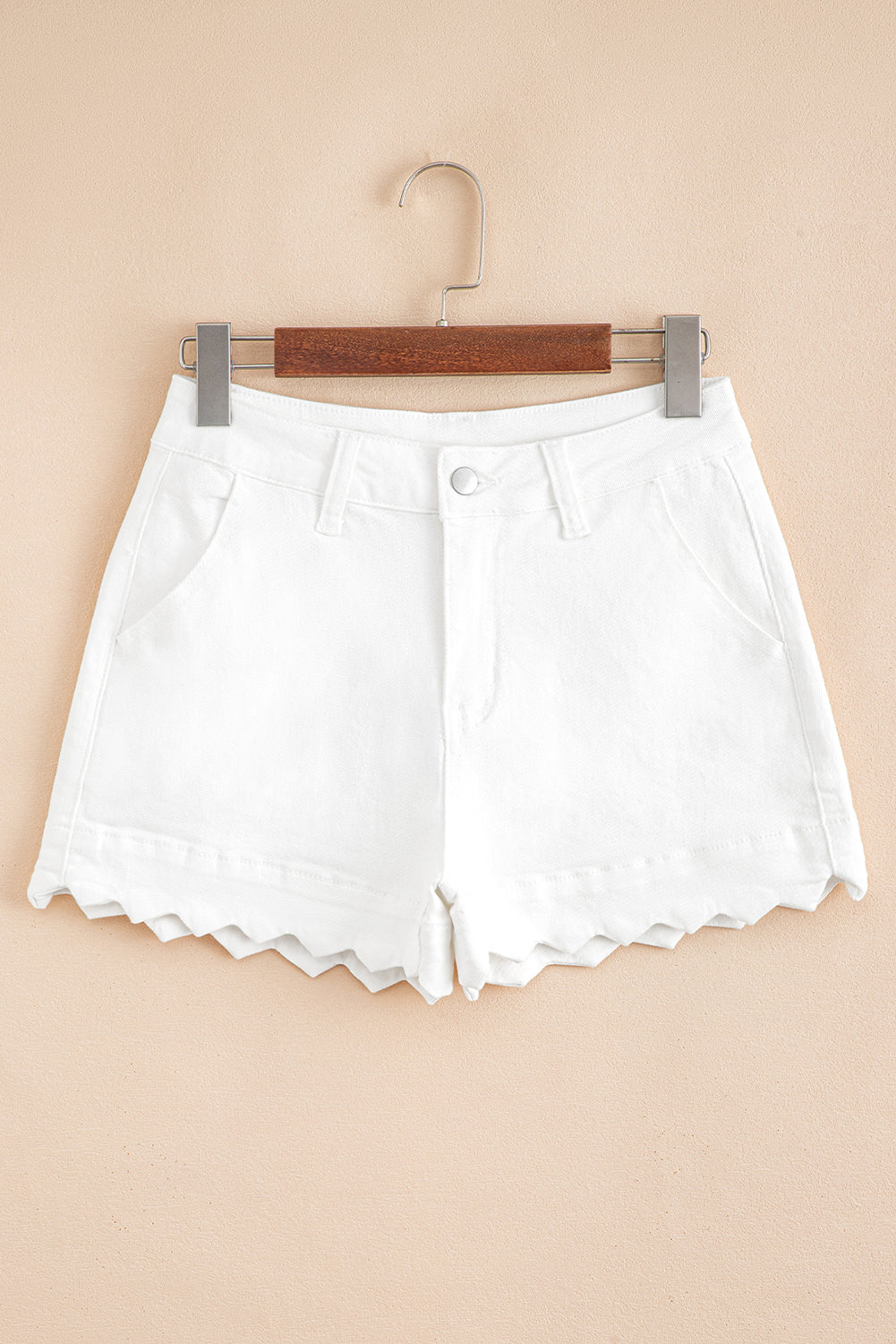 White denim shorts on a hanger against a beige background