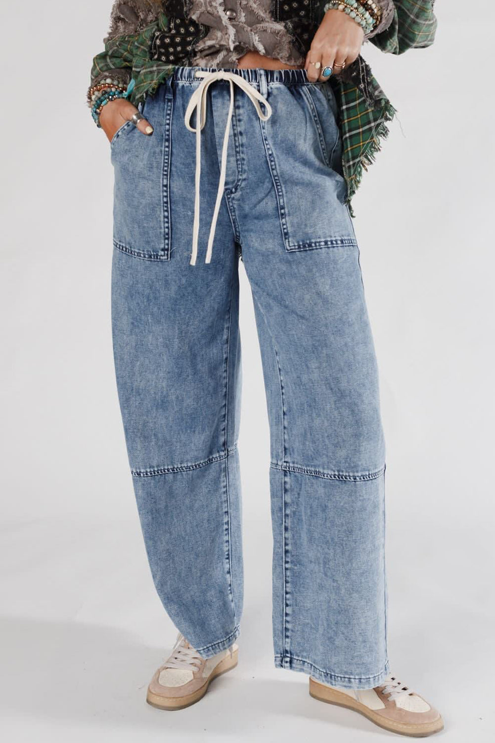 Person wearing blue patchwork jeans with a plain background