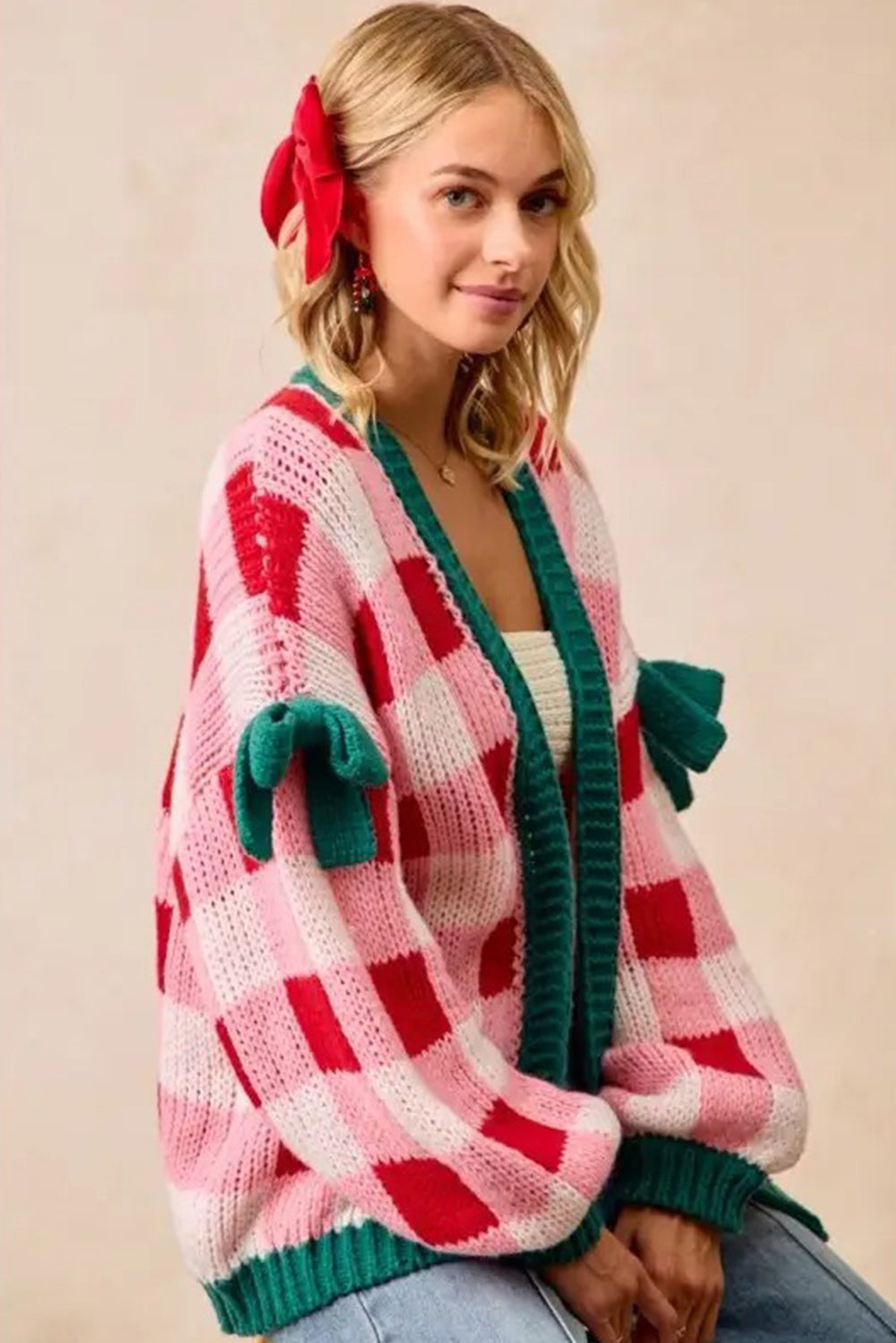 Woman wearing a pink and red checkered cardigan with green accents on a beige background