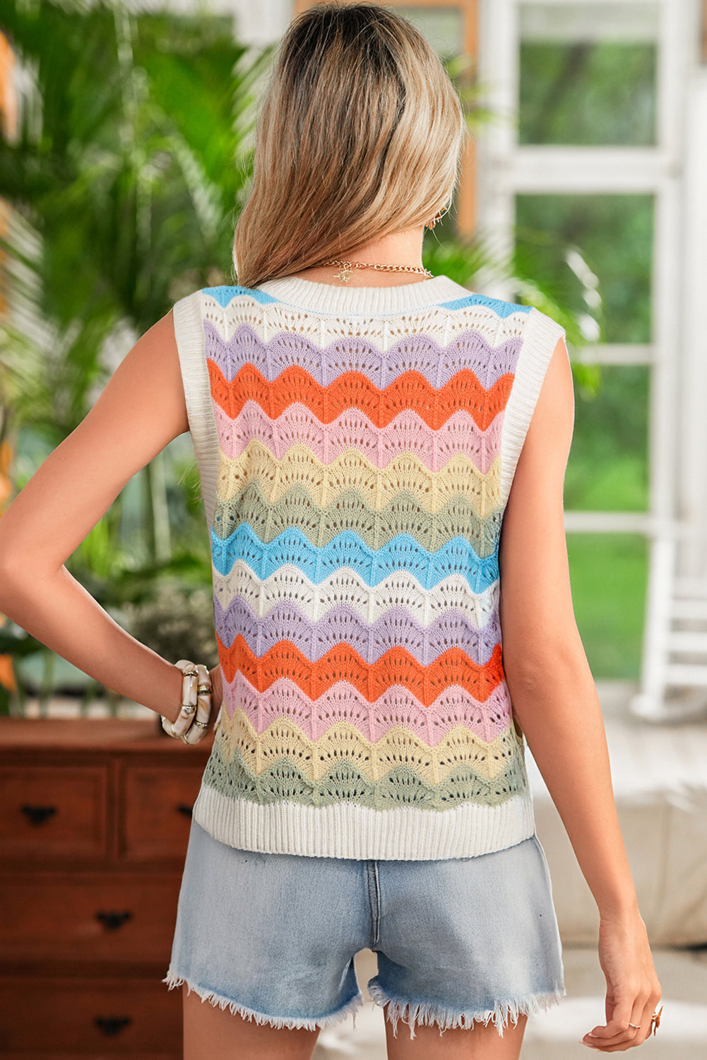 Woman wearing a colorful sleeveless sweater with a blurred indoor background