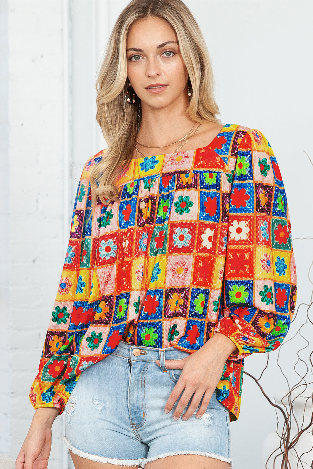 Woman wearing a colorful patchwork blouse with floral patterns against a white background
