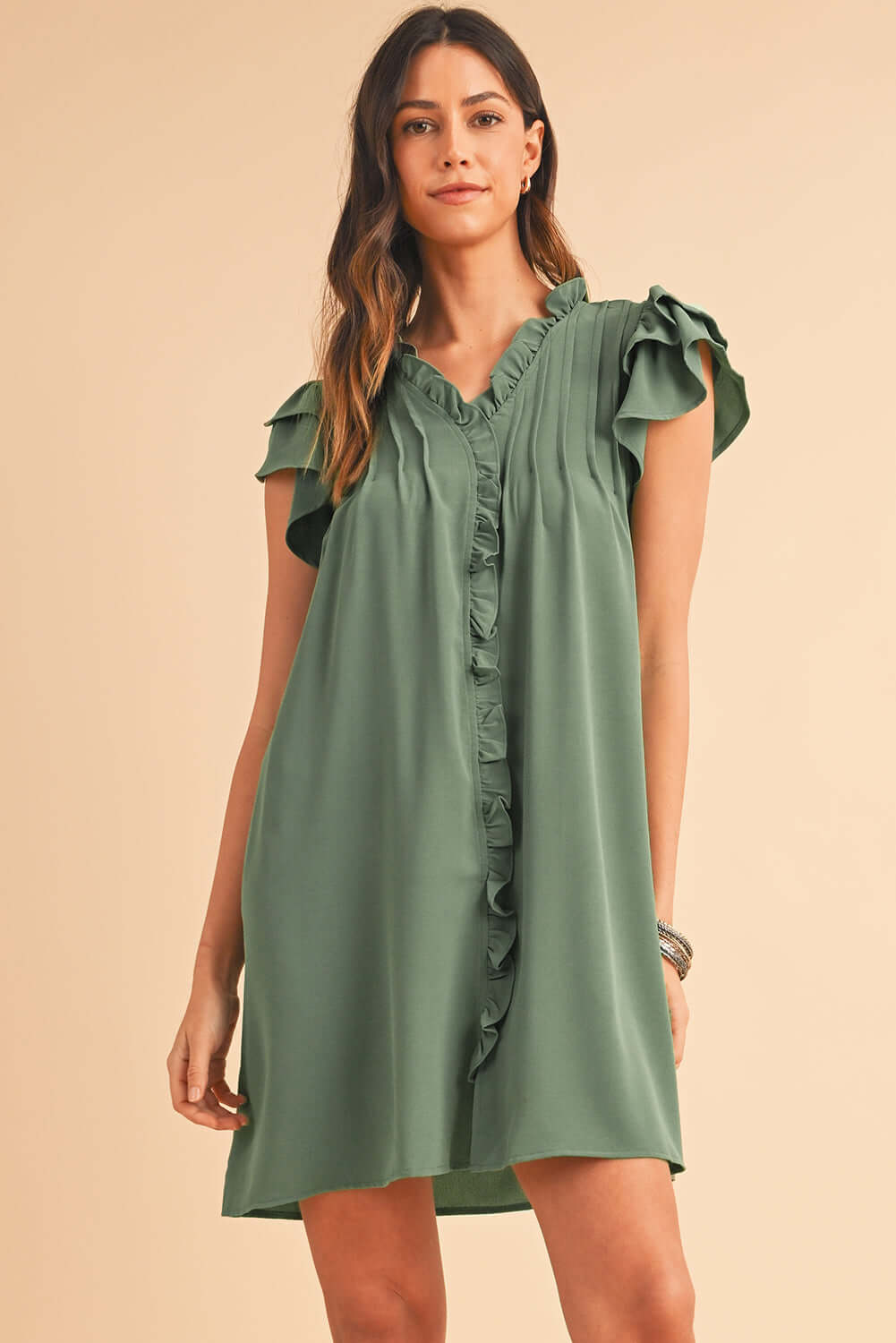 Woman wearing a short ruffle front dress with flutter sleeves and V-neckline.