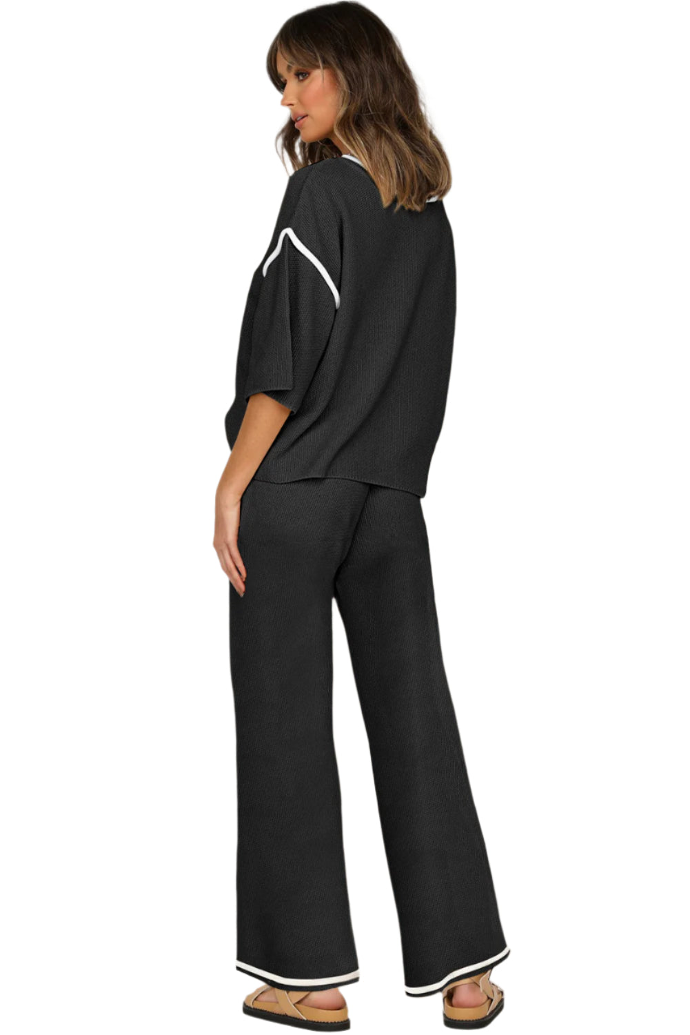 Woman wearing a black outfit with white accents on a plain background