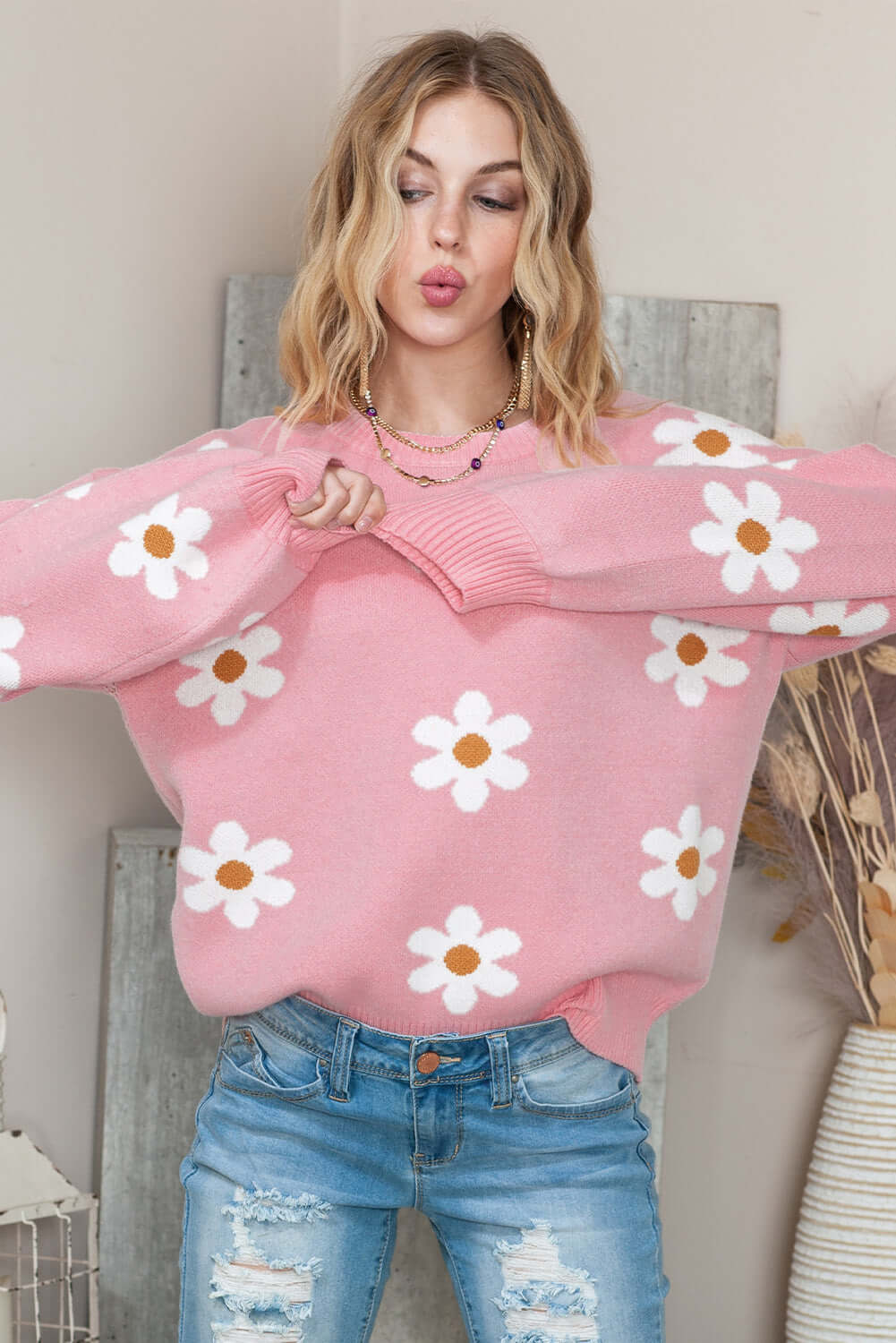Pink flower-printed knit sweater worn by a woman indoor.
