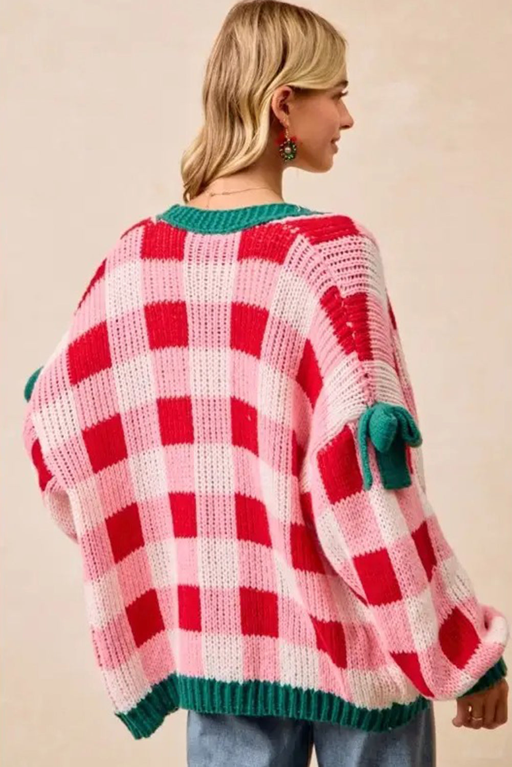 Person wearing a red and pink checkered sweater with green accents on a beige background