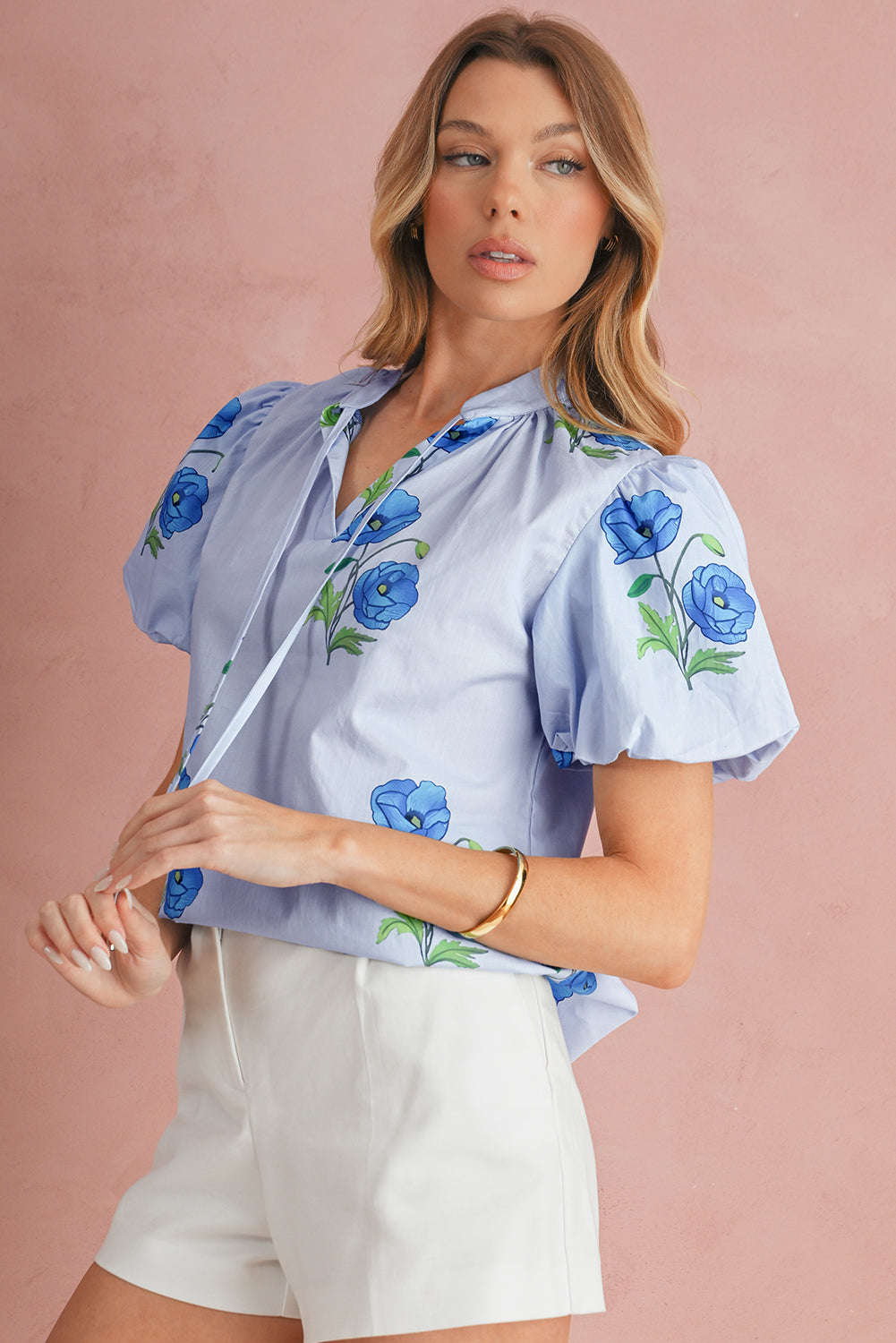 Woman wearing a light blue blouse with floral patterns on a pink background