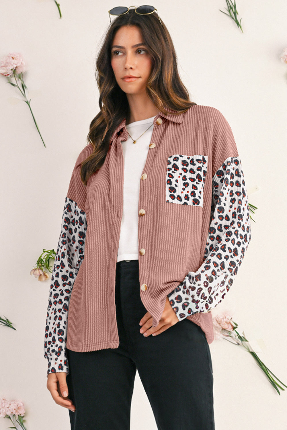 Woman wearing a pink button-up shirt with leopard print sleeves against a light background
