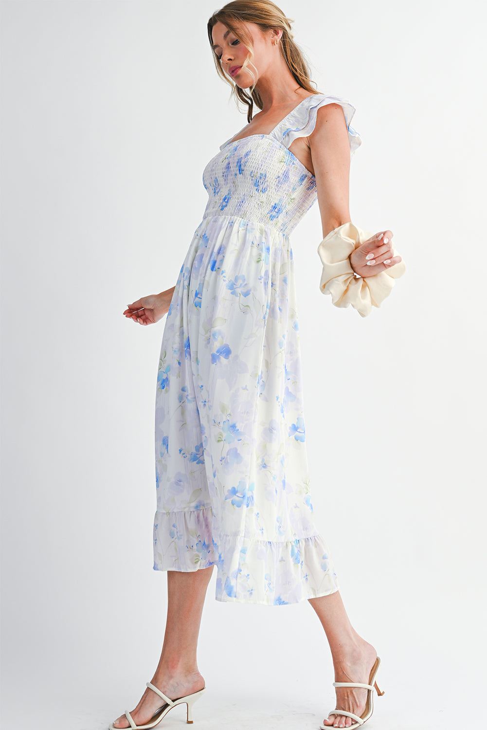 Woman wearing a white floral dress with blue flowers on a plain background
