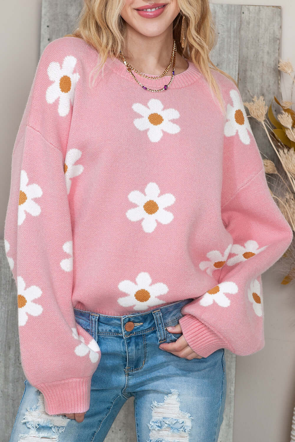 Women's pink knit sweater with flower print, front view closed up.