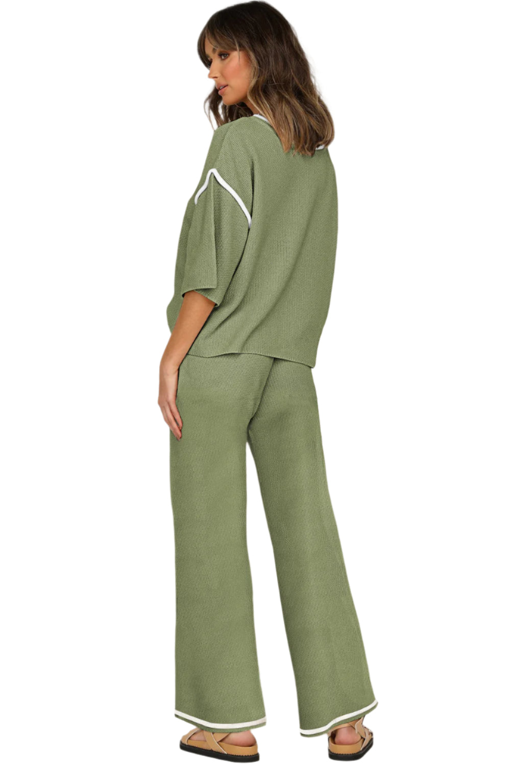 Woman wearing a green outfit with white trim on a white background