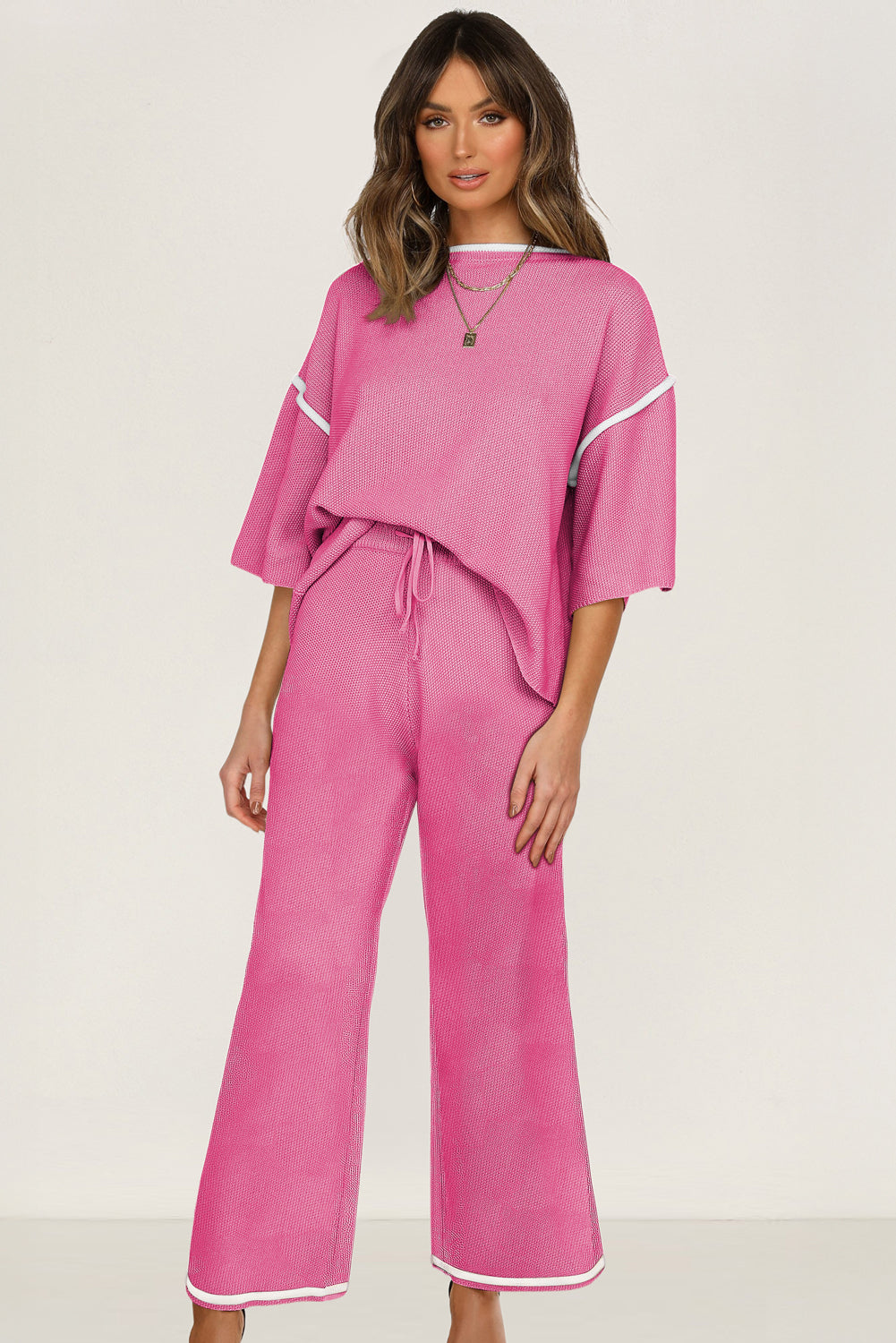 Woman wearing a pink outfit with white trim on a plain background