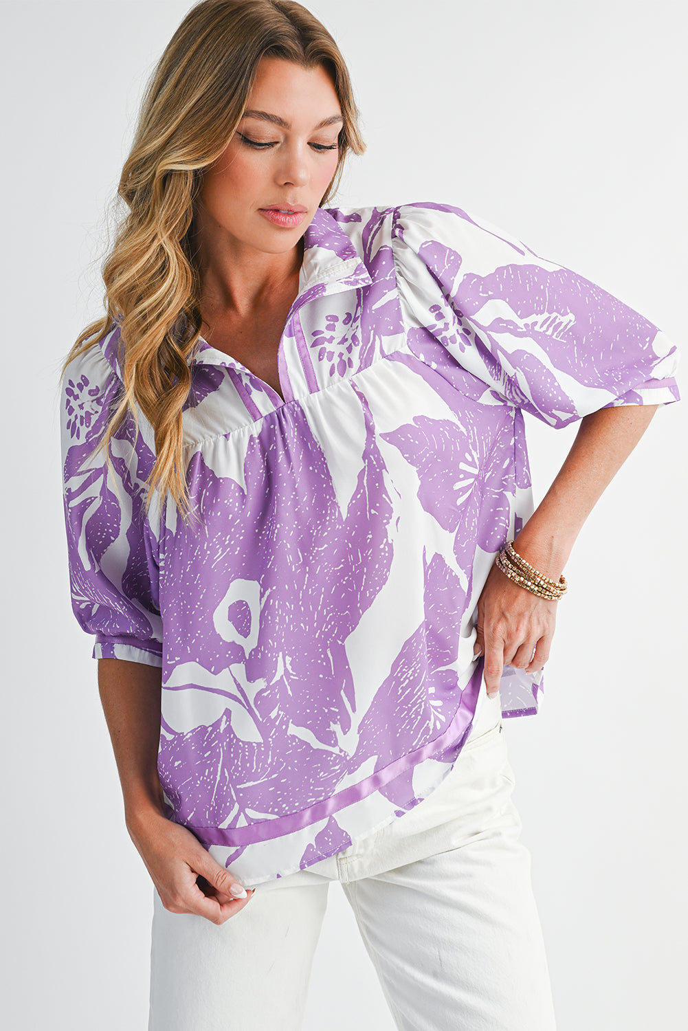 Woman wearing a purple and white patterned blouse with a white background