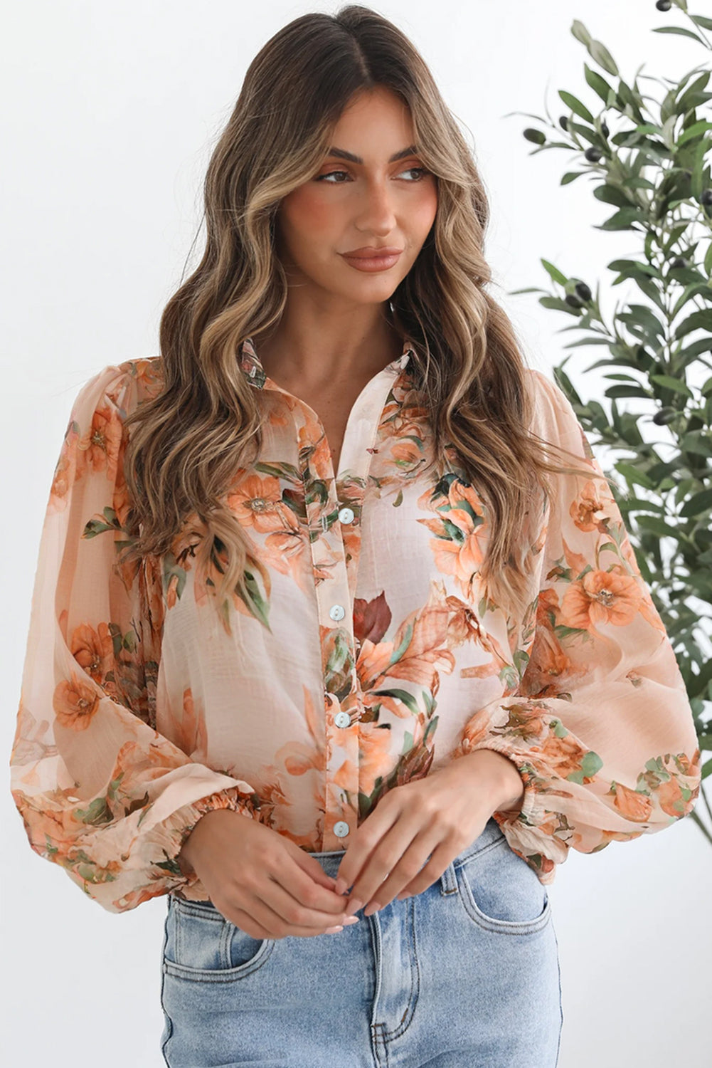 Woman wearing a floral blouse with a blurred green plant in the background