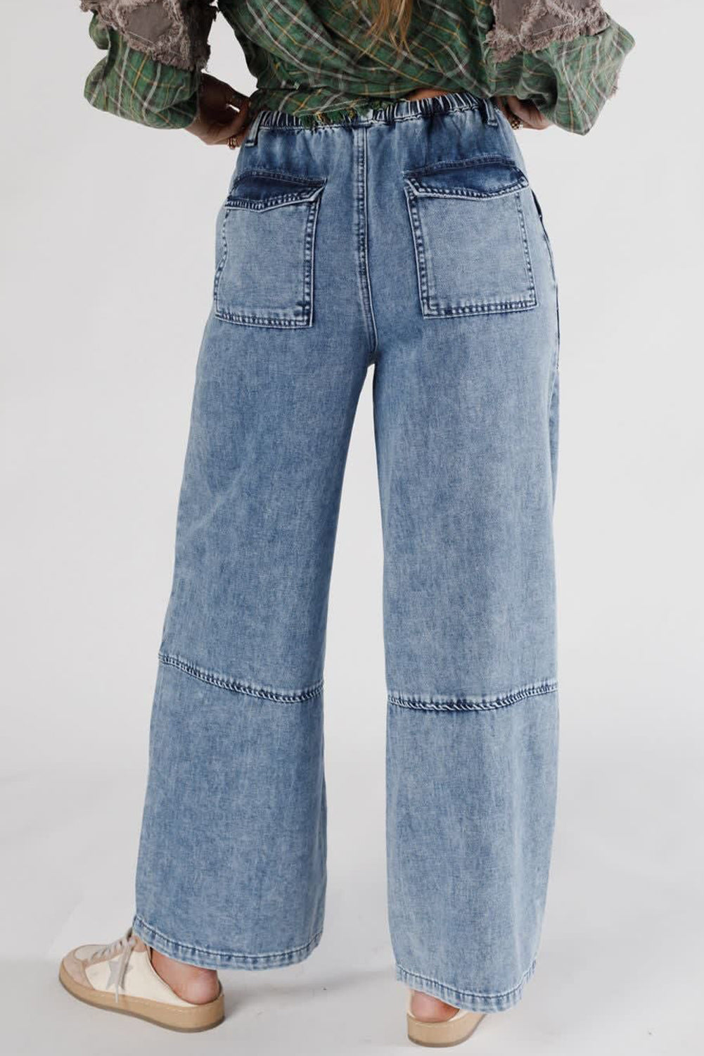 Person wearing high-waisted blue jeans on a plain background