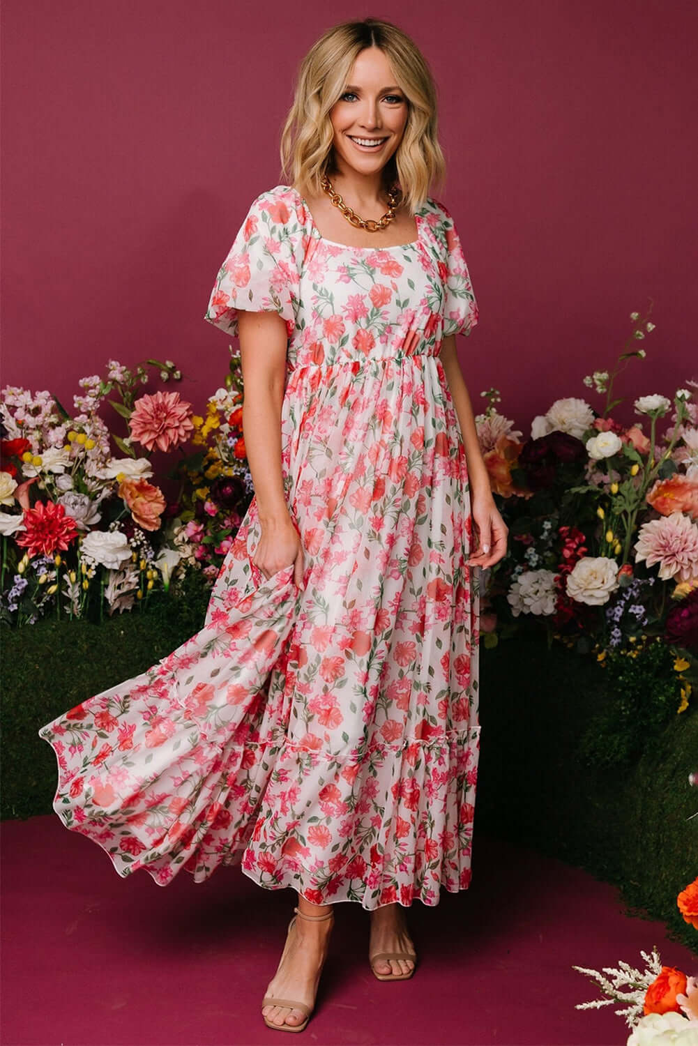 Woman wearing a pink floral puff sleeve maxi dress with a square neckline.