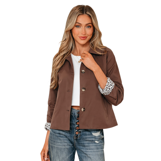 A woman wearing a cropped brown cotton jacket with a classic collar and large tonal buttons, featuring leopard print lining visible at the rolled cuffs.