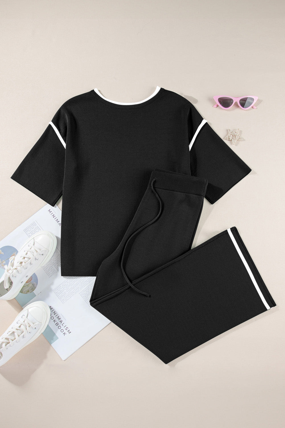 Black outfit with white accents on a beige surface