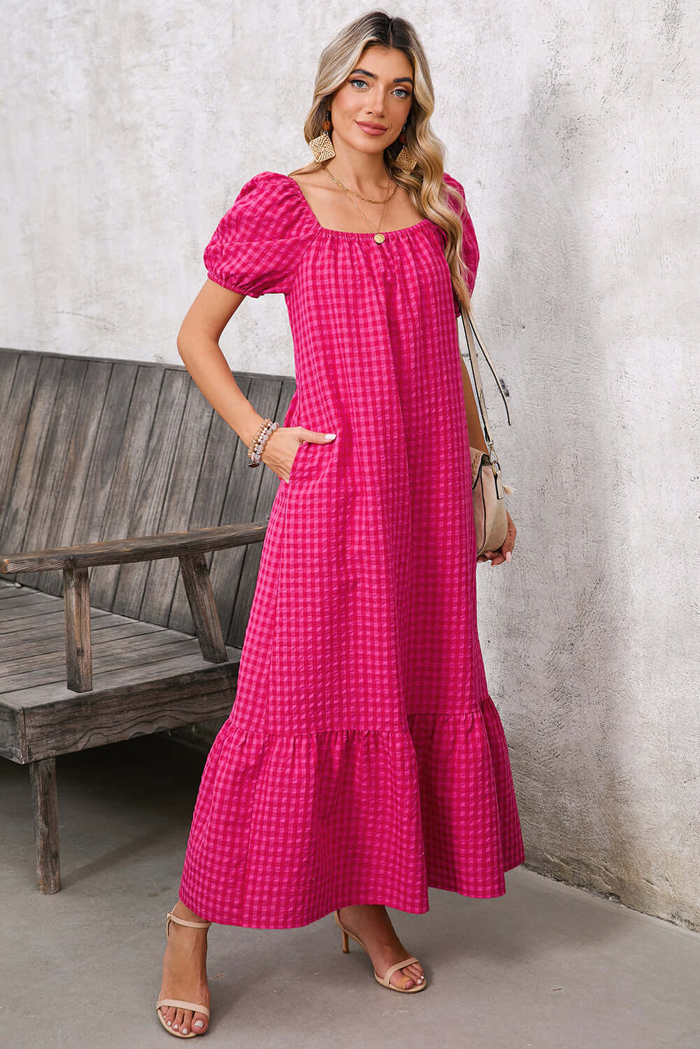 Model styling a pink gingham maxi dress with gold accessories and neutral heels for a chic summer look.