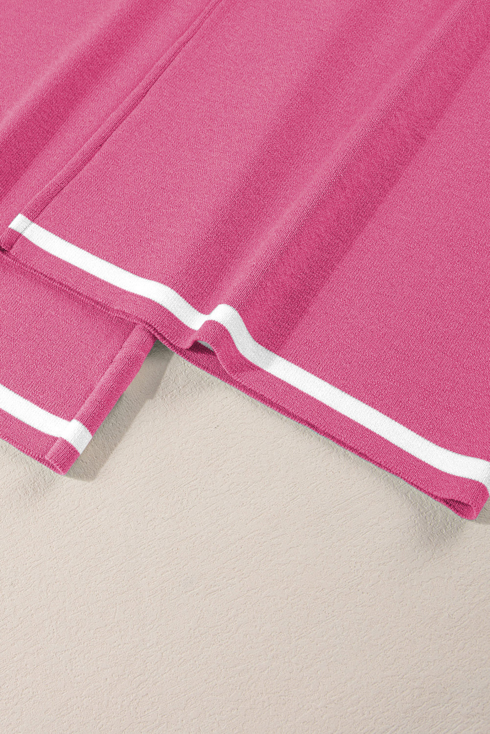 Close-up of a pink fabric with white trim on a beige background