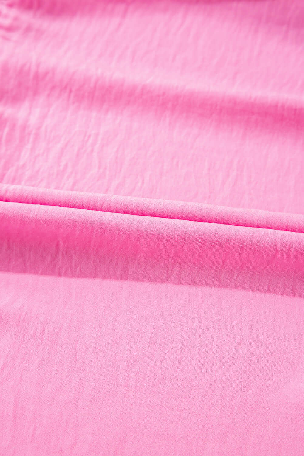 Close-up of a lightweight pink dress with a halter neckline and soft ruffles.