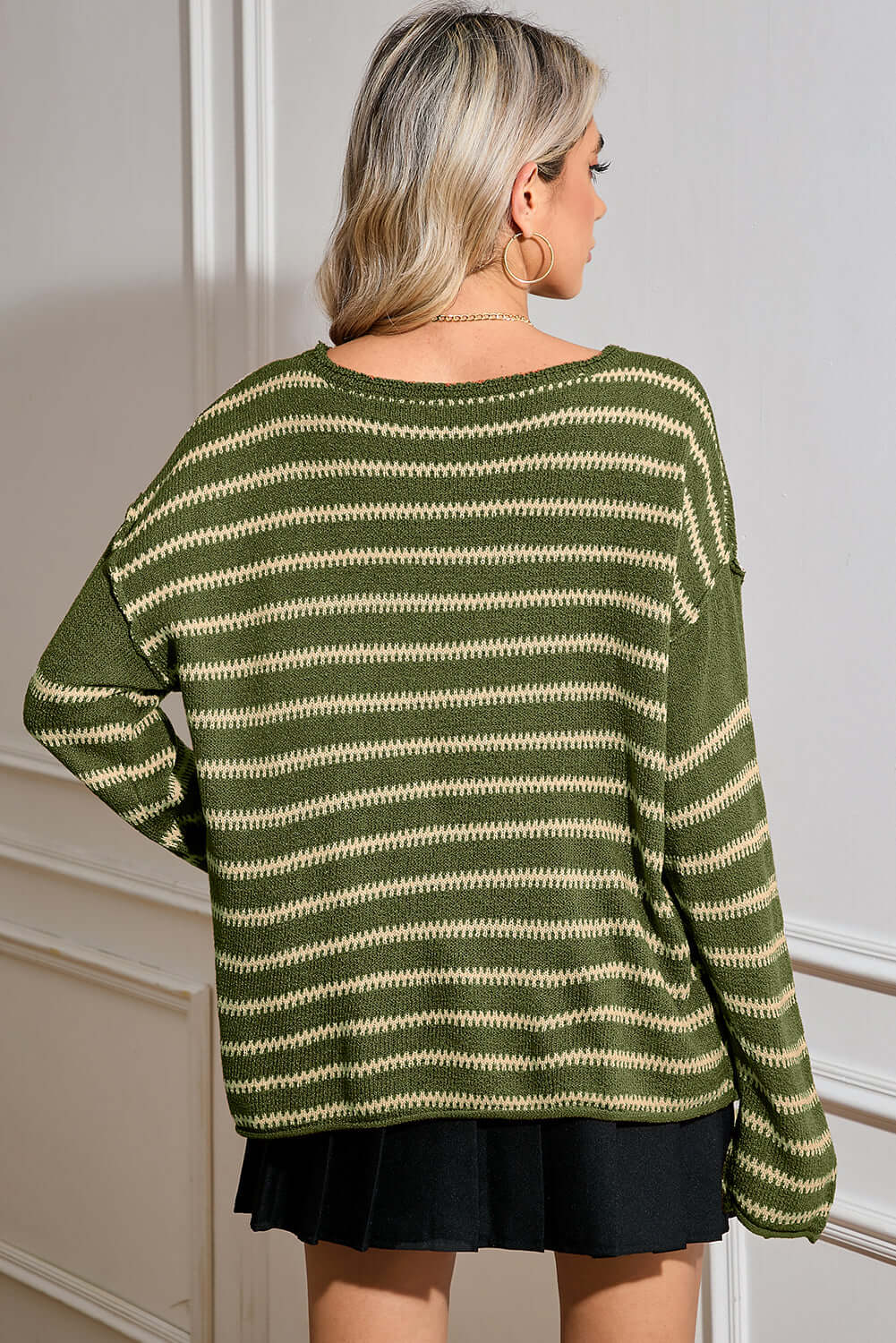 Back view of the green striped jumper, highlighting its relaxed drape and long sleeves.