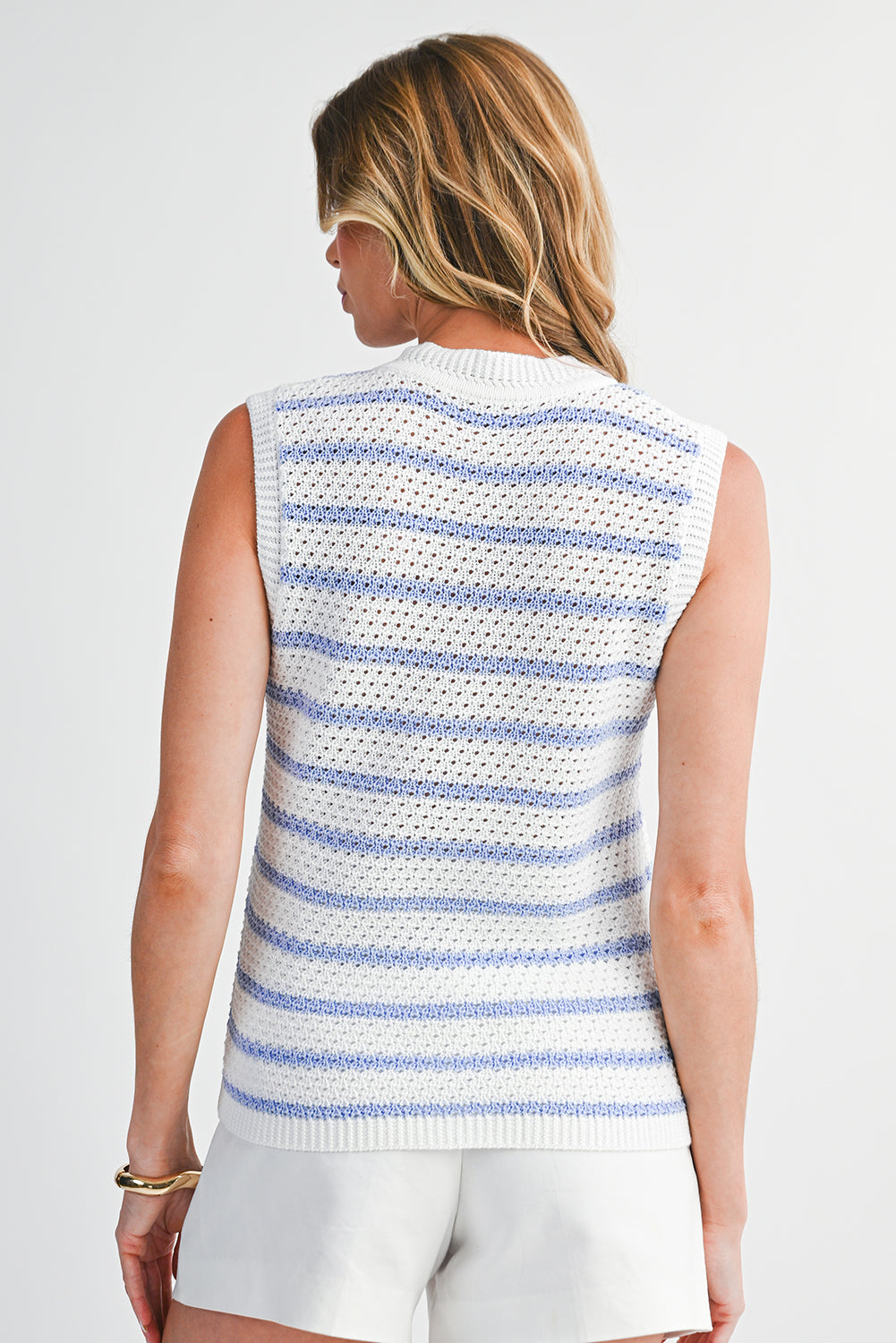 Woman wearing a sleeveless striped sweater on a plain background