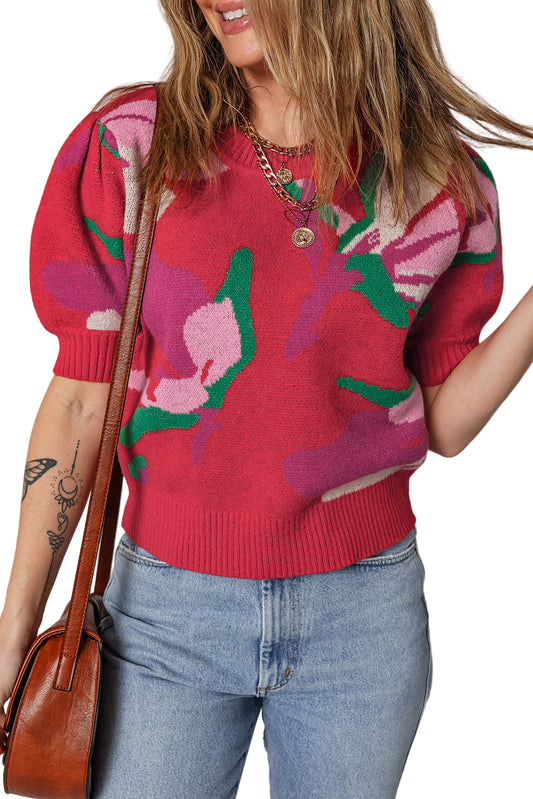 Person wearing a red floral sweater with blue jeans and a brown bag.