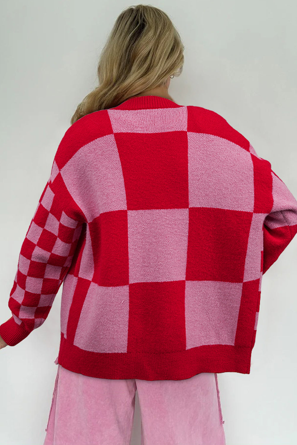 Person wearing a red and pink checkered sweater against a white background