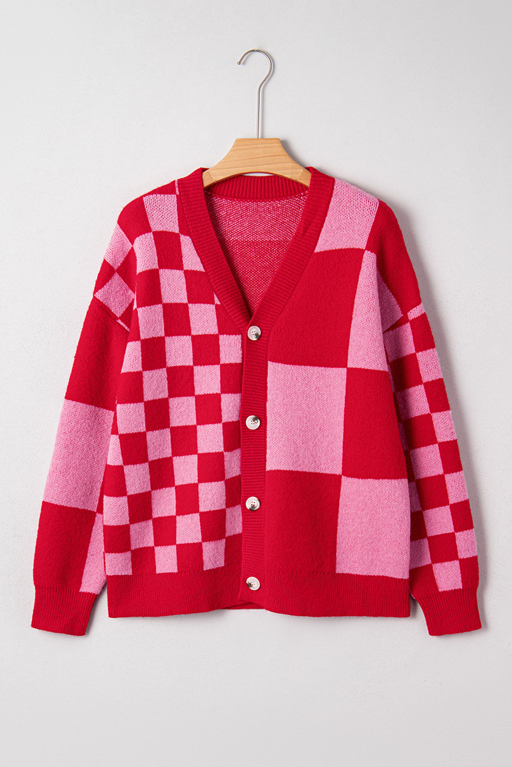 Red and pink checkered cardigan on a hanger against a white background