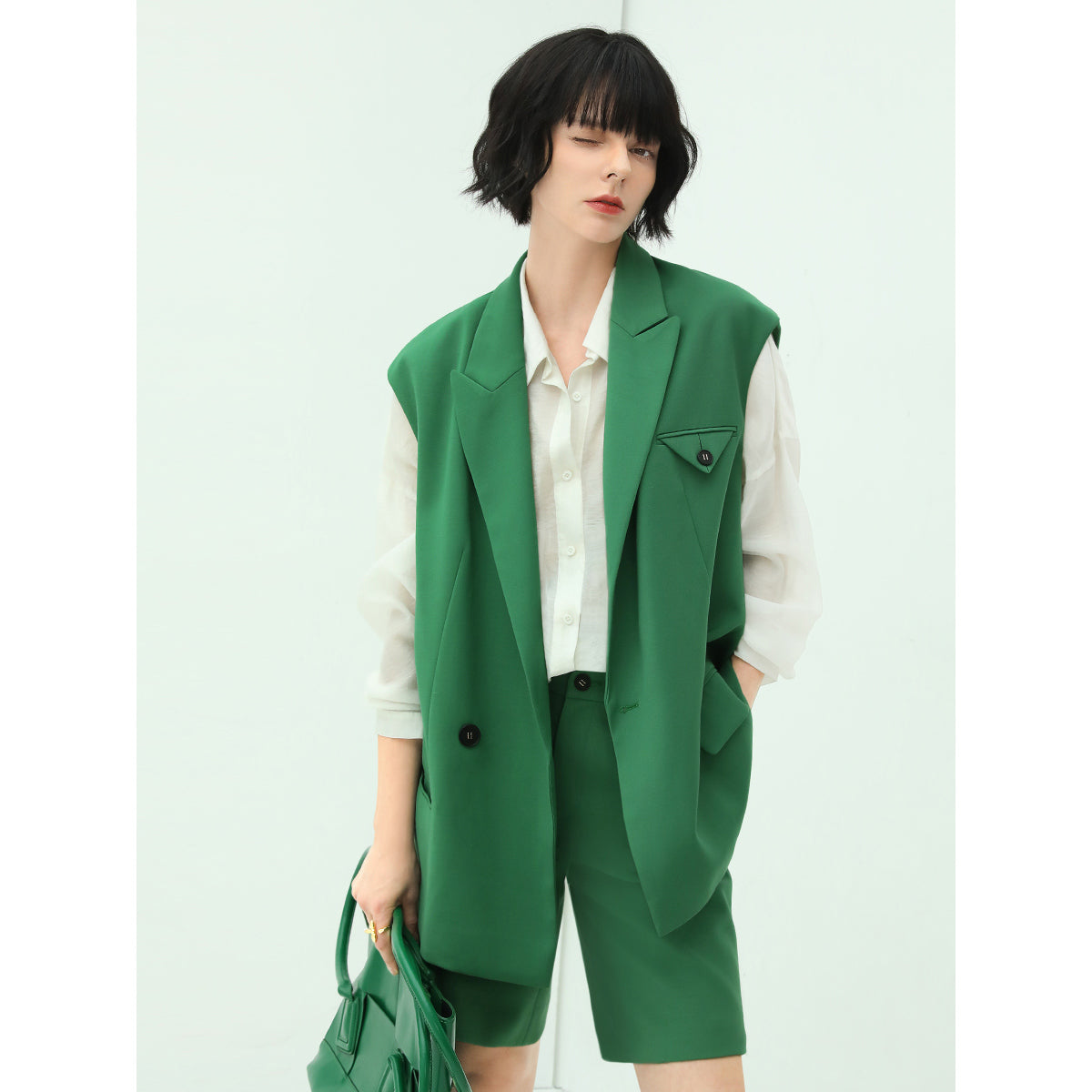 Person wearing a green vest over a white shirt with a white background
