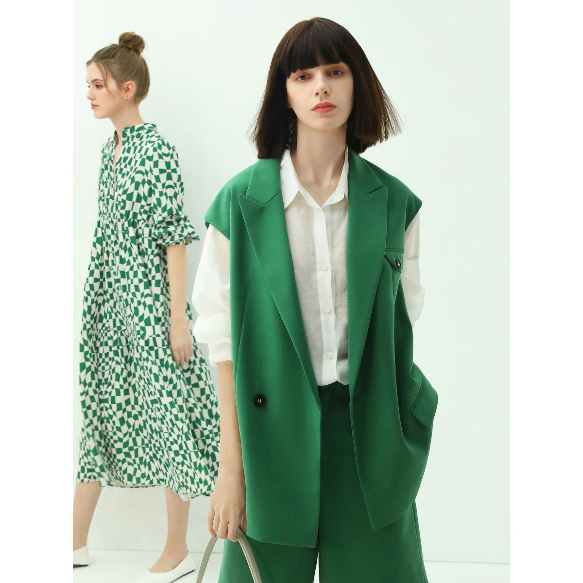 Two women wearing green and white outfits on a white background
